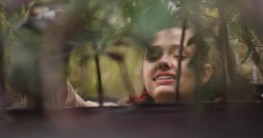 Genç bir kadın, bir bahçe merkezinde metal bir sulama tenekesi kullanarak bitkileri sulamaktan hoşlanıyor. Sahne, bahçıvanlığın ve bitki bakımının özünü yakalıyor..