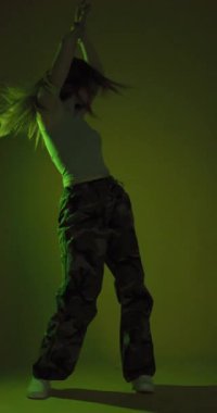 Disko partisinde, arka planda renkli ışık parlamaları olan bir bayan. Dans eden kız hip hop ağır çekim dikey video. 
