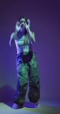 Disko partisinde, arka planda renkli ışık parlamaları olan bir bayan. Dans eden kız hip hop ağır çekim dikey video. 