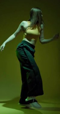 Hip hop dansı yapan kız yavaş çekim dikey video. Disko partisinde, arka planda renkli ışık parlamaları olan bir bayan..