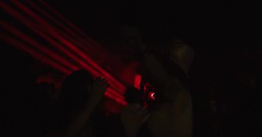 İki genç kız dans ediyor ve sahnenin önünde kalabalığın içinde zıplıyorlar. Düşük ışık videosu. 120fps 'te yavaş çekim kaydedici..