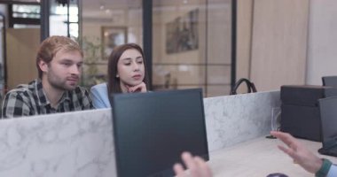 Genç bir çift modern bir ofiste bir danışmanı dikkatle dinler. Bir iş toplantısındalar, önemli konuları tartışıyorlar..