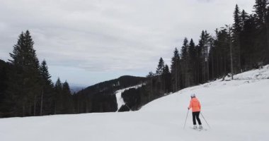 Bir kayakçı, el değmemiş kar ve yükselen ağaçlarla çevrili yumuşak bir yamaçta zarifçe süzülür. Sakin kış manzarası dağlarda mükemmel bir kaçış sağlıyor..