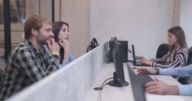 Genç bir çift modern bir ofiste bir danışmanla iş tartışıyor. Diğer çalışanlar özenle arka planda çalışıyor..