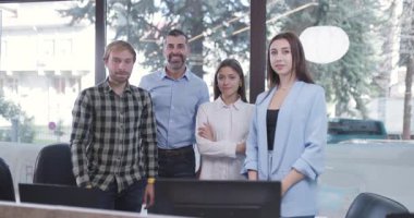 Dört iş adamı modern ofislerinde kameraya güvenle gülümsüyor. Takım çalışması, işbirliği ve iş hayatında başarı..