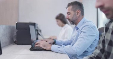 Ofisteki insanlar dizüstü bilgisayarlar ve bilgisayarlar üzerinde çalışıyorlar. İş arkadaşları takımı. Saha videosunun derinliği. Geriye dönük kamera hareketi.