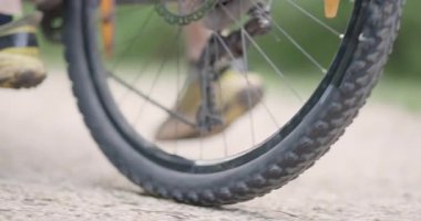 Soyut dağ bisikletçisi binmeye hazırlanıyor. Kirli bir patikada dağ bisikleti süren bir adam. Kapalı pedal ayakkabı ve vites kolu. Sinema kamerasında 120 fps 'de kaydedildi..