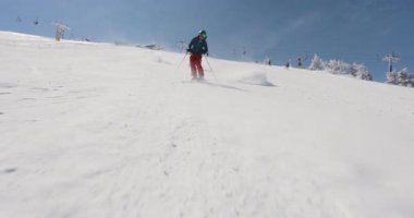 Aydınlık bir kış gününde, kayakçılar nefes kesen dağ yamaçlarında taze toz gezerler. Kar güneşin altında parıldıyor, zahmetsizce arazide süzülürken, kışın eğlencesini kucaklarken..