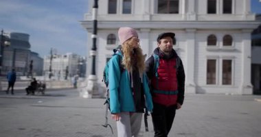 Sırt çantalı genç bir adam ve kadın şehir macerası manzarası ve seslerinden zevk alarak bir şehri keşfediyorlar..