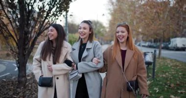 Üç bayan arkadaş, soğuk bir sonbahar gününde el ele yürür ve dışarıda sohbet ederler..