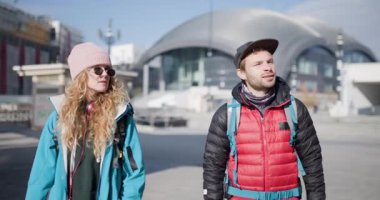 Sırt çantalı genç bir adam ve kadın yeni bir şehri keşfederken yürür ve konuşurlar. Etrafa bakınıp çevrelerini tartışıyorlar..