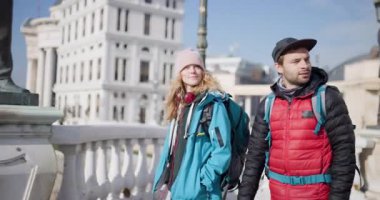 Sırt çantalı genç bir çift güneşli bir günde şehir merkezinde yürür ve birlikte tatilin tadını çıkarırlar..