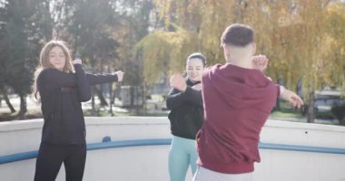 Parkta birlikte ısınan üç arkadaş. Kentsel bir ortamda fitness, refah ve aktif yaşam tarzını teşvik etmek.