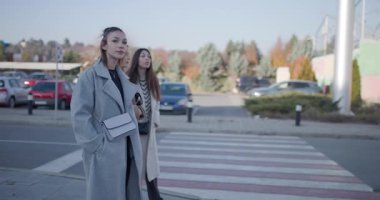 Üç modaya uygun arkadaş, yaya geçidinde bekliyorlar, bir sonraki hedefleri hakkında konuşurken işaret edip gülüyorlar..