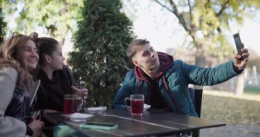 Kafenin dışında çay içip cep telefonu kullanan arkadaşlar. Arkadaşlığın neşesini ve birlikteliğini yakalamak..