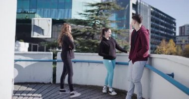 Egzersiz yaparken sohbet eden bir grup arkadaş. Yaya geçidinin eğri bir bölümünde duruyorlar..