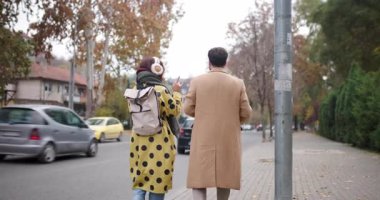 Genç bir çift bir sonbahar caddesinde yürüyor, canlı sohbetler yapıyor ve birbirlerinin yanında eğleniyorlar..