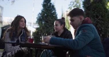 Arkadaşlar açık bir kafede toplanır, güneşli bir günde çay eşliğinde hikayeler ve kahkahalar paylaşırlar. Arkadaşlık ve bağlantı.