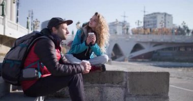 İki arkadaş, erkek ve kadın, sırt çantalı, nehirde kahve molası veriyorlar. Seyahat, turizm, seyahat konsepti.