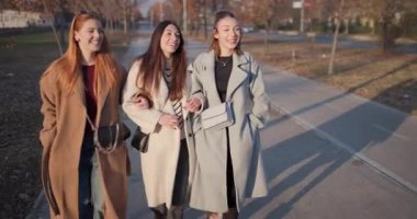 Havalı bayan arkadaşlar yürür, sohbet eder ve güler altın saat boyunca parkta yürürken..