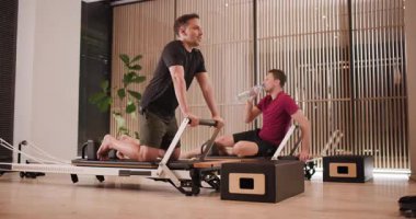 İki birey şık bir fitness stüdyosunda yenilikçi ekipman kullanarak egzersiz yapıyorlar. Güçlerini ve esnekliklerini arttırdıkça atmosfer enerjik ve odaklı..