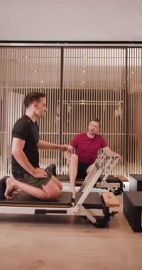 İki adam direniş eğitimi alıyor, iyi ışıklandırılmış bir spor salonunda çeşitli egzersizler yapıyorlar. Özel ekipman kullanarak güç ve fitness tekniklerine odaklanırlar..