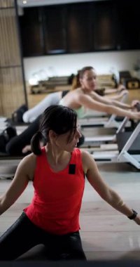 Katılımcılar bir fitness stüdyosunda temel güç ve esneklik eğitimi alıyorlar. Hareket ve tekniklere rehberlik eden eğitmenlerle atmosfer enerjiktir..