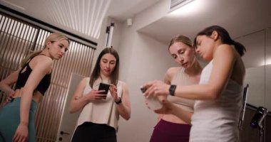 Çağdaş bir spor salonunda işbirliği yapan bir grup kadın, cihazlardaki verileri kontrol ederken fitness stratejilerini tartışıyor. Atmosfer odaklı ve motive edici, takım çalışmasını teşvik ediyor..