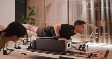 Katılımcılar, çekirdek egzersizleri ve uygun formu vurgulayarak dinamik bir pilates egzersizi yapıyorlar. Şık stüdyo doğal ışık ve modern ekipmanlara sahip, motive edici bir atmosferi teşvik ediyor..