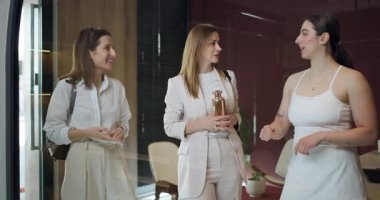 Üç kadın şık bir ortamda, elinde dekoratif bir şişeyle hareketli bir konuşma yapıyorlar. Ayarlar zarafet ve modern tasarım yayar..