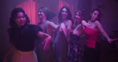 Beş kız arkadaş renkli ışıklar altında bir ev partisinde dans ediyor ve eğleniyorlar..