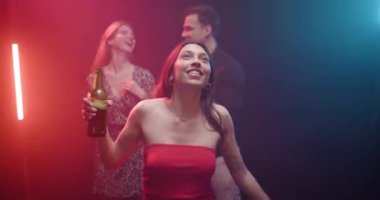 Renkli neon ışıkları ve dumanlı atmosferi olan bir partide dans eden ve içen arkadaşlar..