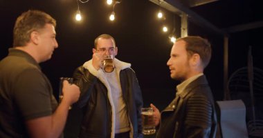 Üç arkadaş, açık havada toplanan biralardan hoşlanırlar. Sohbete dalarlar ve sıcak sicim ışıkları altında kahkaha atarlar..