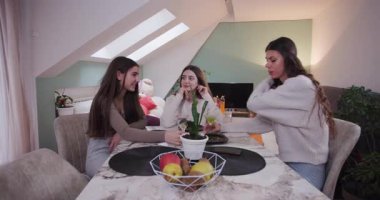 Üç arkadaş, pijama partisi için sıcak bir oturma odasında toplanıyor. Evde eğlenceli bir akşamda birlikte eğlenirken kahkahalar ve atıştırmalıklar paylaşıyorlar..