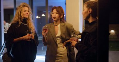 Üç modaya uygun kadın şık bir akşam partisinde içki içip sohbet etmekten zevk alıyor. Arkadaşlar, kutlama ve birliktelik..