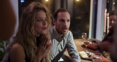 Arkadaşlar akşam yemeği için şarap, peynir ve şarküteri ile bir araya gelirler. Bir adam telefonuyla selfie çeker..