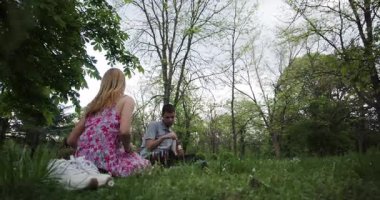 Parkta romantik bir pikniğin tadını çıkaran, yemek ve içkileri paylaşan bir çift. Adam eğlence olsun diye baloncuk yapıyor..