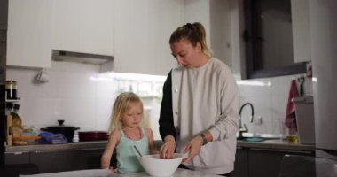 Anne ve kızı mutfakta birlikte kurabiye yapıyorlar. Hamur yuvarlıyorlar ve eğleniyorlar..