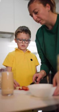 Bir anne, küçük oğlunun milkshake 'ini mutfakta çilekle süslemesine yardım eder. Birbirlerine bağlanıp eğlenceli ve sağlıklı bir ziyafet çekiyorlar..