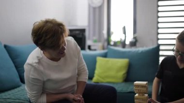 Büyükannem ve torunum birlikte bir oyun oynuyorlar. Tahta bloklardan bir kule inşa ediyorlar ve eğleniyorlar..