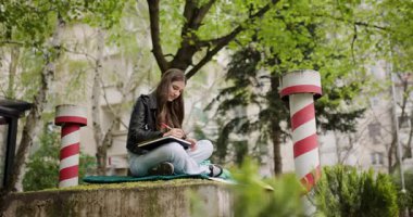 Park 'ta Dışarıda Çalışan Genç Kız: Odaklanmış Bir Öğrenci Temiz Havanın ve Doğanın tadını çıkarırken Not Alıyor