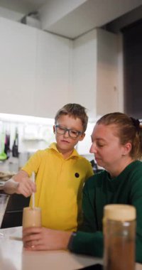 Bir anne ve oğlu mutfakta milkshake 'in tadını çıkarırlar. Çocuk içkisine şeker katıyor ve birbirlerine sarılıyorlar..