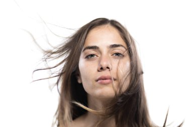 Soluk soluklu saçlarıyla beyaz bir arkaplan üzerinde doğal ve sakin bir ifade yayan genç bir kadının yakın çekim portresi..