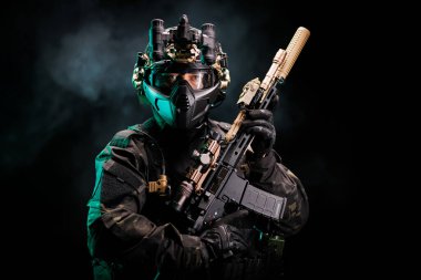 Taktik teçhizat ve gece görüşü teçhizatı giymiş bir asker karanlık atmosferik bir ortamda güç, ihtiyat ve modern muharebe hazırlığını vurgularken sofistike bir silah bulundurur..