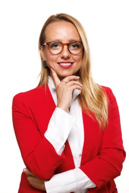 Bir iş kadını, kırmızı bir ceket ve beyaz bir gömlek içinde duruyor, gülümseyerek çenesini eline dayıyor, profesyonelliği ve başarıyı bir stüdyo arka planında somutlaştırıyor..