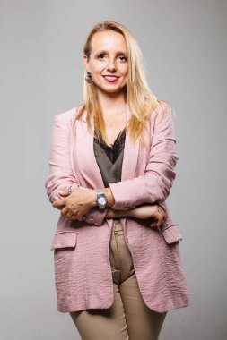 Kendine güvenen bir iş kadını kollarını kavuşturup spor ceket ve pantolon içinde şık bir görünüm sergiliyor. Bir iş etkinliğine hazır, profesyonellik ve özgüven yayıyor..