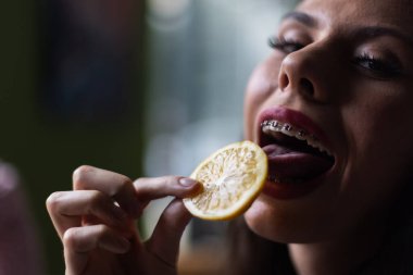 Diş teli takmış, limon tatmış, eğlenceli ve çağdaş bir anı gösteren bir kişinin detaylı bir görüntüsü..