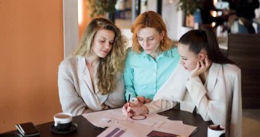 Üç iş kadını şık bir işyeri kafesinde strateji ve planlar üzerine odaklanmış bir tartışmaya girişiyor. Etkin bir şekilde işbirliği yapıyorlar, çizelgeler ve belgeler üzerinde görüşlerini paylaşıyorlar..