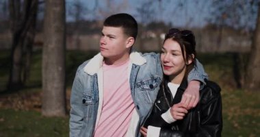 Genç bir çift güneşli bir günde birbirlerine eşlik ederek parkta birlikte yürür. Yürürken gülümser ve konuşurlar..