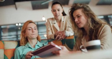 Üç iş kadını canlı bir kafede verimli bir tartışmaya girişiyor. Notlarını ve beyin fırtınası fikirlerini paylaşıyorlar. Başarı odaklı yaratıcı bir ortamda takım çalışması sergiliyorlar..